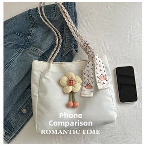 Detail of off-white tote bag featuring braided handles and floral silk scarf charm