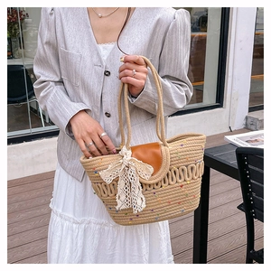 Détail d'un sac seau en paille bohème avec pois colorés, nœud en dentelle et rabat en cuir