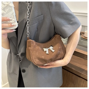 Brown semi-circle hobo bag with silver bow accent and metal chain strap on model