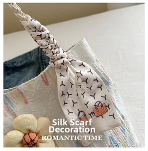 Detailed close-up of white tote bag with floral charm and scarf-wrapped handle decoration