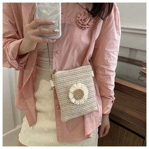 Close-up of beige straw woven crossbody bag with delicate daisy floral appliques