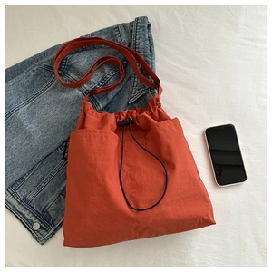 Detailed top view of orange nylon tote bag with drawstring closure and black toggle