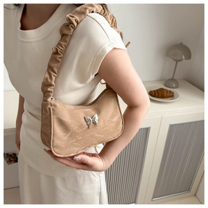 Detail of light brown ruched shoulder bag with silver butterfly clasp and pleated strap