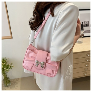 Detail of pink bow shoulder bag with silver metallic buckle on high-gloss synthetic leather