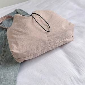 Pink casual tote bag in textured fabric on white background with denim jacket