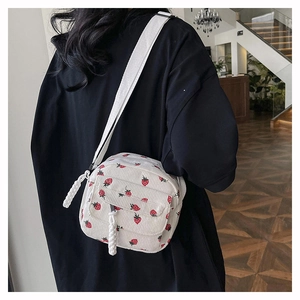Detailed back view of a corduroy crossbody bag with strawberry print on a model
