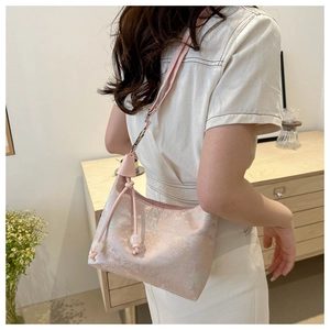 Detail of pink floral jacquard handbag with silk texture and adjustable leather strap