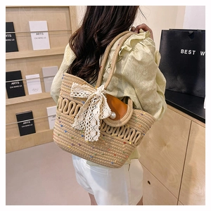 Detail of straw tote bag with white lace bow and pearl button on brown flap