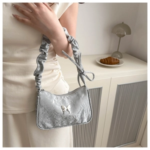 Détail du sac à main argenté métallisé avec poignée froncée et décor de papillon
