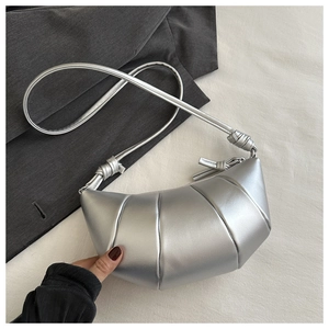 Detail shot of silver crescent bag with metallic faux leather texture on grey blazer