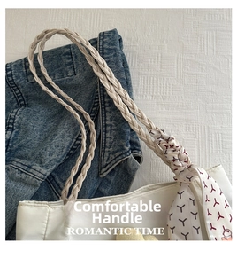 Detail of white tote bag featuring woven handles and stylish beige silk scarf accent