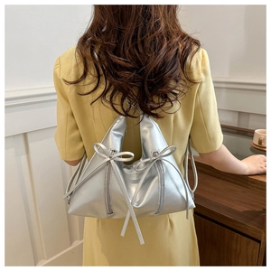 Close-up of metallic silver tote bag with unique triangular shape and side zipper details