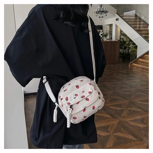Detail of white corduroy crossbody bag with red strawberry prints worn by a model