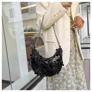 Detail of black sequined hobo bag with silver chain straps on model in city setting