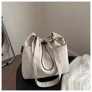 Detail of off-white canvas drawstring tote with side pocket and black adjustable toggle