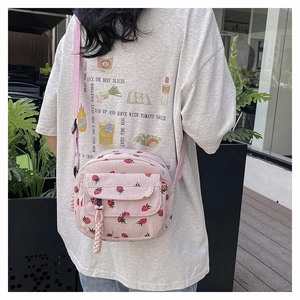 Detail of pink corduroy crossbody bag with cute strawberry pattern and adjustable strap