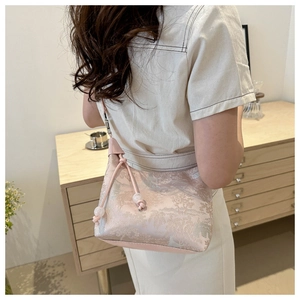 Close-up of pink jacquard fabric handbag with elegant floral patterns and bead detail