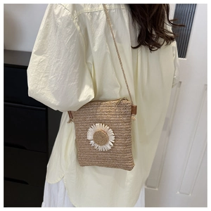 Detail of straw woven crossbody bag with daisy flower showing the wearing style