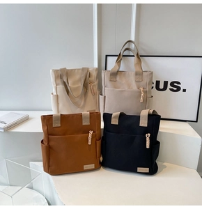 Dettaglio di quattro borse tote in tela color avorio, beige, marrone e nero con tasche laterali