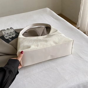 Fashionable cream marble texture tote bag shown on a white bed in a lifestyle setting