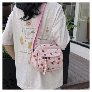 Detailed shot of pink corduroy crossbody bag with strawberry pattern on model