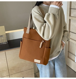 Vista dettagliata della borsa tote in tela marrone con tasca frontale e zip intrecciata
