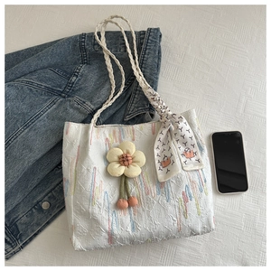 Detailed shot of white tote bag with 3D floral texture and decorative silk scarf