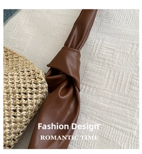 Detail of woven straw tote bag featuring a knotted dark brown leather shoulder strap