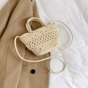 French woven cotton rope handbag with colorful dots and pearl handle on beige fabric