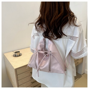 Détail d'un sac à dos en satin rose clair avec des nœuds et des poches zippées