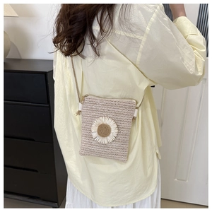Detailed close-up of handmade straw crossbody bag featuring a large 3D daisy flower charm