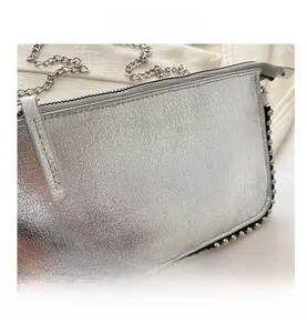 Macro view of silver textured leather bag with metallic rivets and chain strap detail