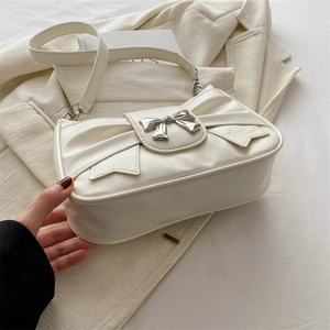 Chic cream white PU leather shoulder bag with silver bow buckle on beige blazer