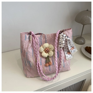 Detailed texture of pink woven tote bag with floral charm and printed handle scarf