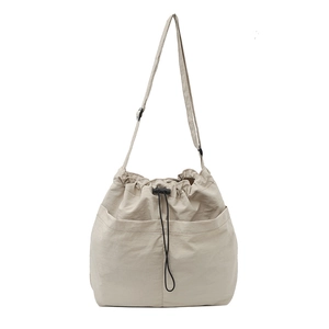 Beige nylon drawstring tote bag with adjustable strap and front pockets for daily commute