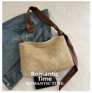 Close-up of woven straw tote bag with brown leather strap and decorative bow detail