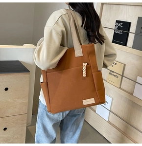 Dettaglio della borsa tote in tela caramello con etichetta moda e tracolla larga