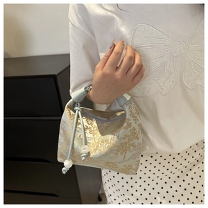 Detail of floral jacquard embroidery and blue leather handle on a vintage handbag