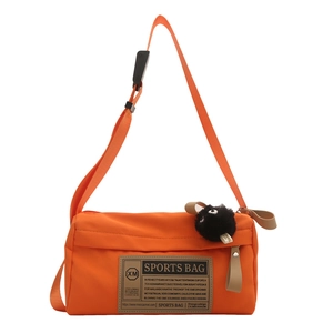 Orange nylon outdoor crossbody bag with a plush monster keychain and sports patch