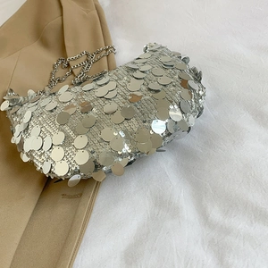 Silver sequin hobo bag with metal chain strap shown on a khaki suit jacket
