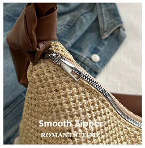 Detail of a woven straw tote with a brown leather knotted handle and silver metal zipper