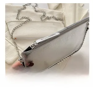 Close-up of smooth silver metallic zipper and ball trim detail on the textured handbag