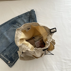 Large beige nylon drawstring tote bag showing spacious interior with cosmetics