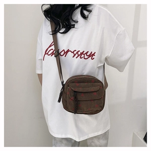 Detail view of brown corduroy crossbody bag with strawberry pattern and front flap pocket