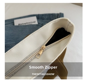 Close-up of smooth gold metal zipper and durable canvas texture on a stylish tote bag