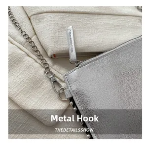 Close-up of polished silver hardware hook and embossed leather texture on a crossbody bag