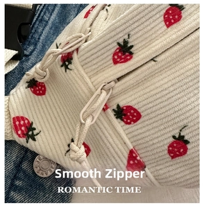 Detailed macro of smooth zipper and strawberry corduroy texture on white crossbody bag