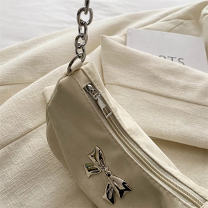Chic cream shoulder bag featuring silver bow hardware and metallic chain strap
