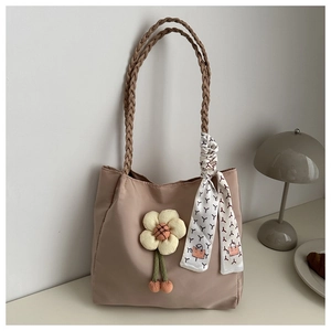 Detail of light khaki tote bag with woven handles, floral charm and silk scarf accent