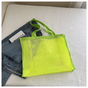 Dettaglio della borsa in rete verde neon con scritte bianche su sfondo lifestyle casual